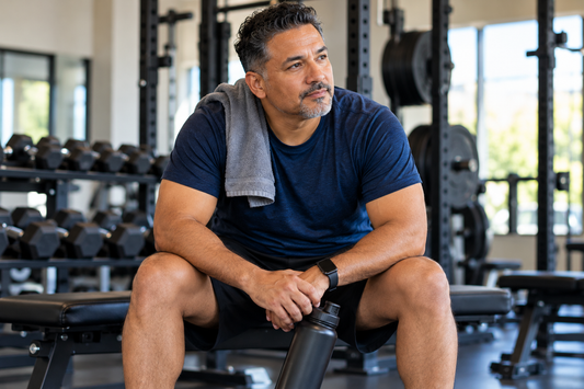 Man in his 40s sitting on a gym bench while restarting his exercise routine