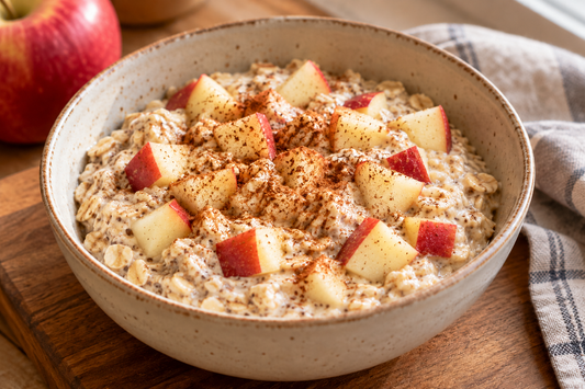 Apple-cinnamon overnight oats with red-skinned apple pieces in a bowl on a kitchen counter.